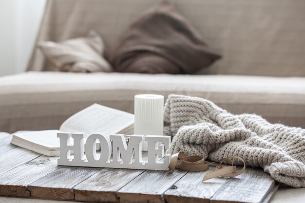Decorative wooden word home, book, candle and knitted element on blurred background.