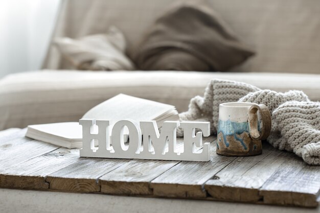 Decorative word home, cup, book and knitted element in the interior of the room.