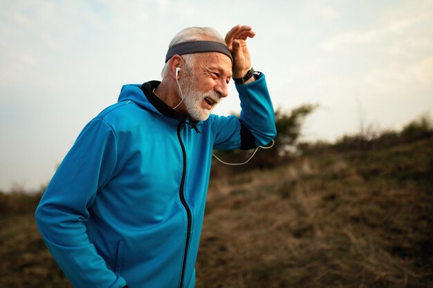 Dedicated senior athlete feeling exhausted while running in the park Copy space