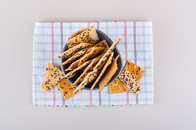 Deep bowl of crackers with black seeds on white background. High quality photo