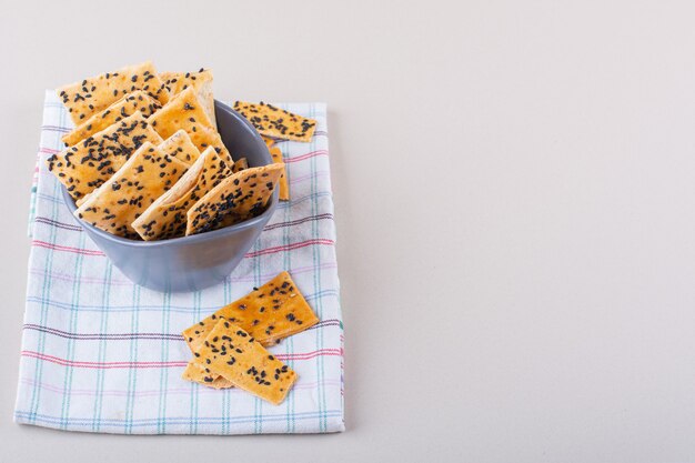 Deep bowl of crackers with black seeds on white background. High quality photo