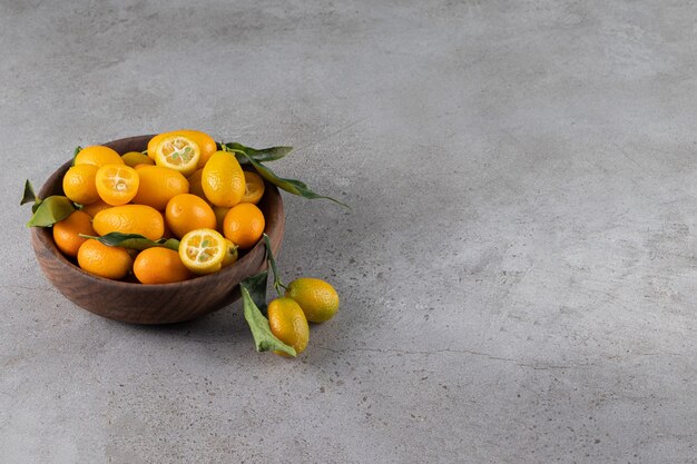 Deep bowl of fresh juicy kumquats on stone surface
