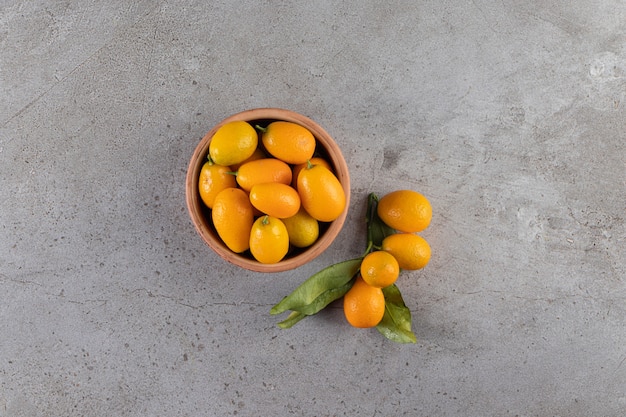 Ciotola profonda di kumquat succosi freschi sul tavolo di pietra.