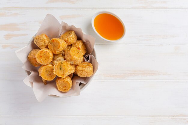 Deep fried fhicken roll on the white wooden surface.