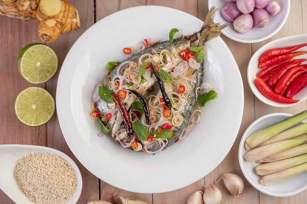 Deep-fried mackerel topped with galangal, pepper, mint, red onion in a white dish.