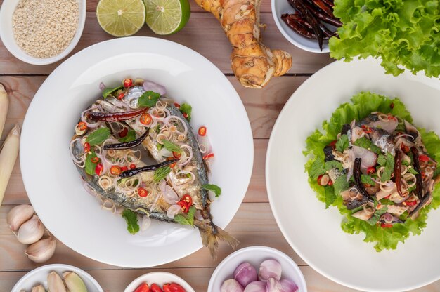 Deep-fried mackerel topped with galangal, pepper, mint, red onion in a white dish.