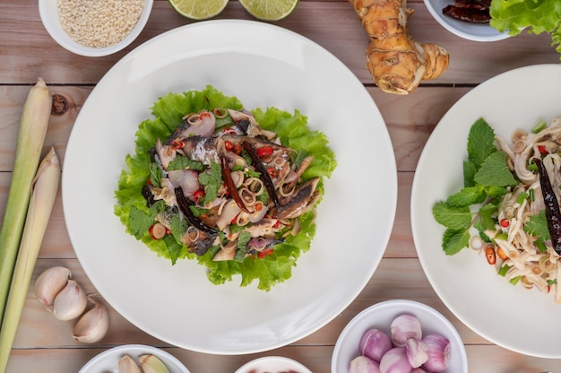 Free photo deep-fried mackerel topped with galangal, pepper, mint, red onion in a white dish.