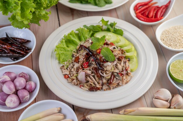 Deep-fried mackerel topped with galangal, pepper, mint, red onion in a white dish.