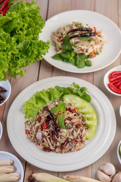 Deep-fried mackerel topped with galangal, pepper, mint, red onion in a white dish.