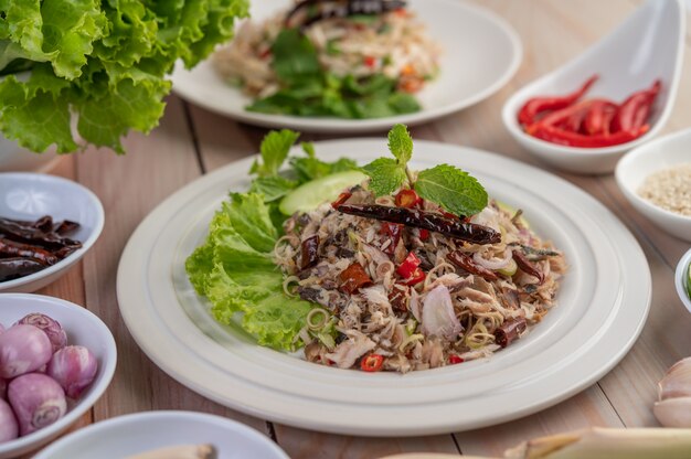 Deep-fried mackerel topped with galangal, pepper, mint, red onion in a white dish.