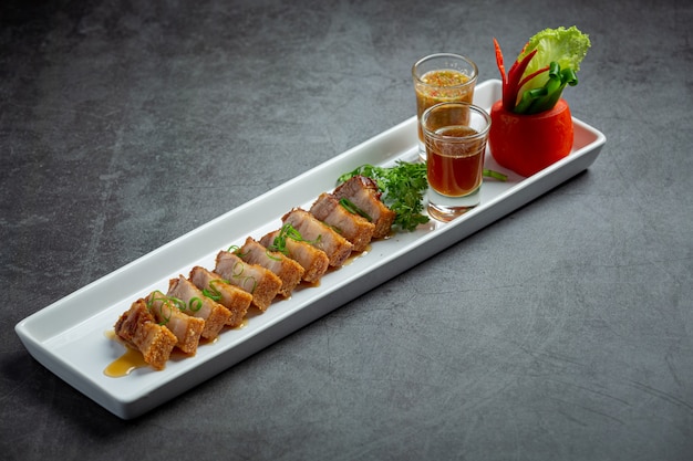 Deep fried pork belly with fish sauce on dark background