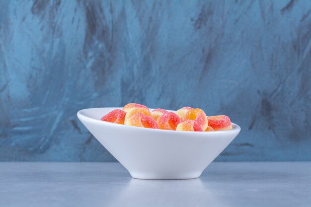 Глубокая тарелка, полная ярких фруктов и сладкого мармелада. Фото высокого качества