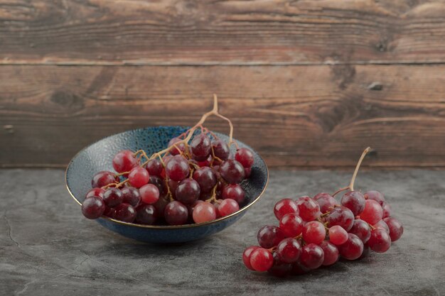 Deep plate of red ripe grapes on marble table. 