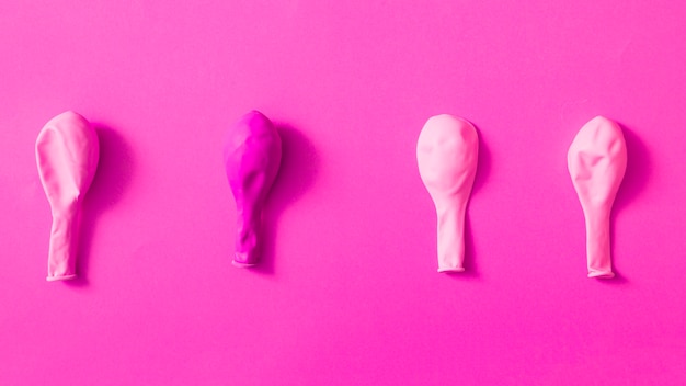 Deflated pink balloons over colored background