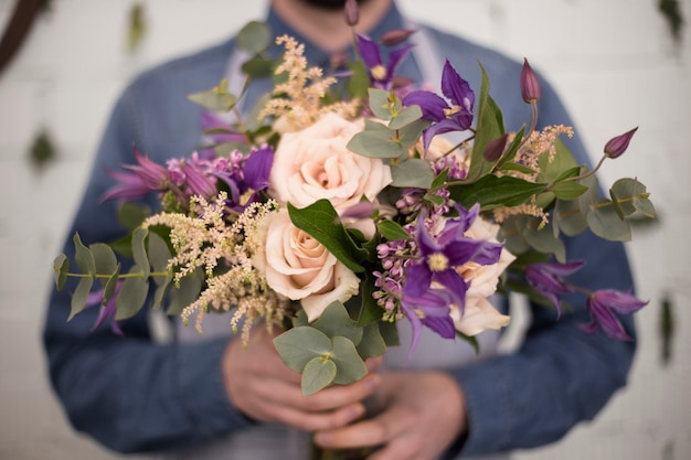 デフォーカス男性の花屋の花の花束を手で押し