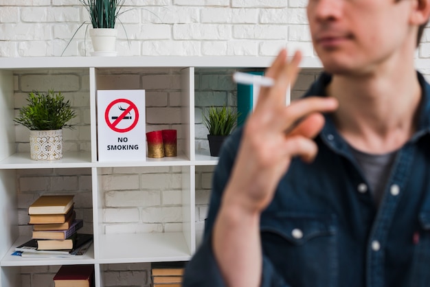 선반에 금연 포스터 앞에서 담배와 함께 defocus 남자
