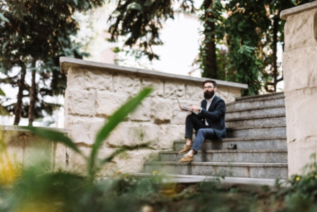 Defocused businessman using laptop in the park