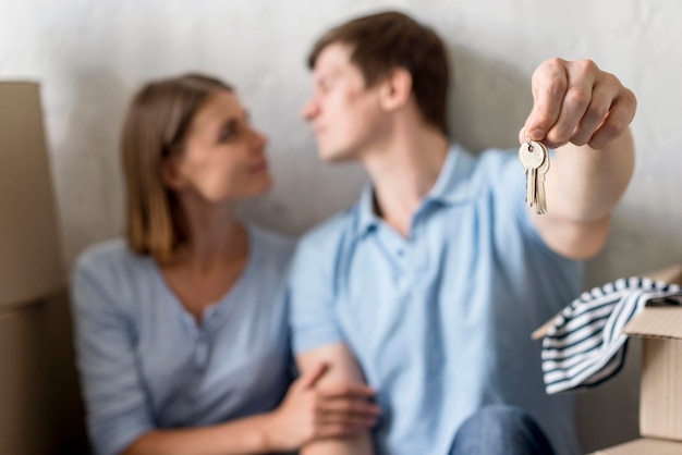 Free photo defocused couple holding keys to old property before moving out