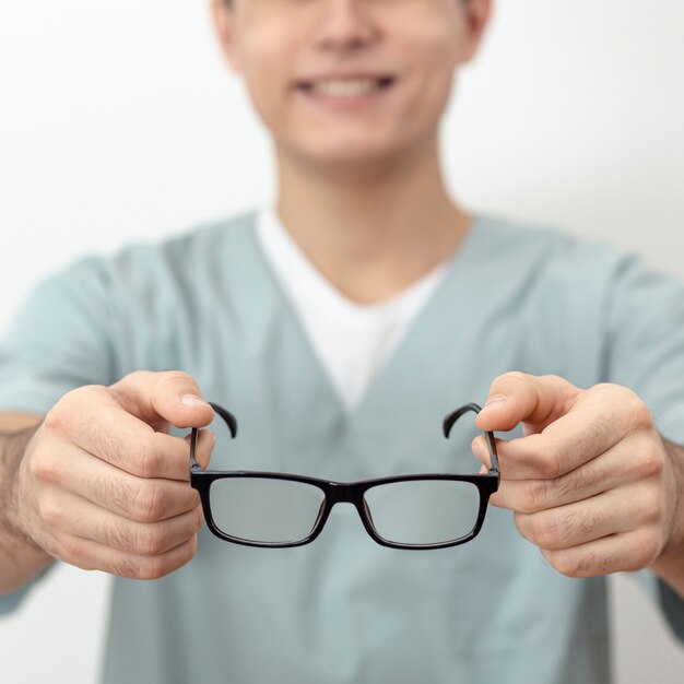 Defocused eye specialist holding pair of glasses