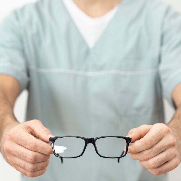 Defocused eye specialist showing off pair of glasses