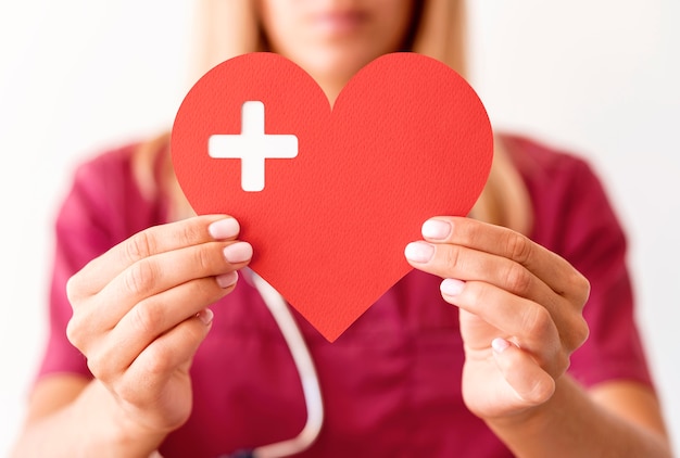 Defocused female doctor holding paper heart