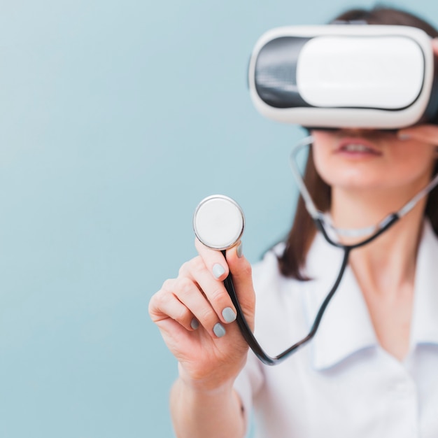 Defocused female doctor using virtual reality headset and stethoscope