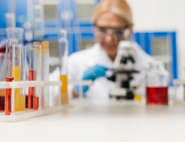 Free photo defocused female scientist in the lab working with microscope