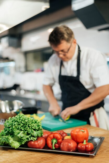 Defocused male chef cutting vegetables