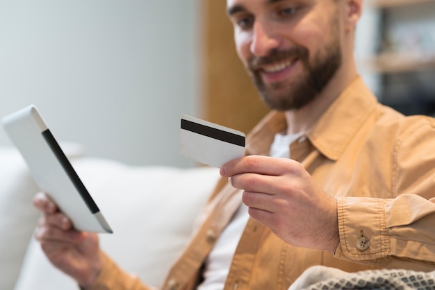 Defocused man holding credit card and tablet