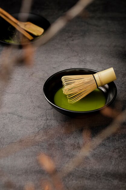 Defocused matcha tea in bowl with bamboo whisk