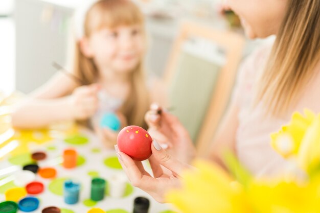 Defocused mom and daughter painting eggs