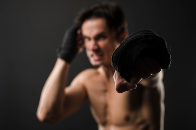 Defocused shirtless muscly man with boxing gloves