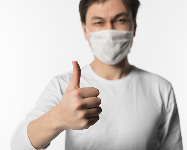 Free photo defocused sick man with medical mask giving thumbs up