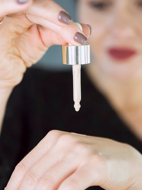 Defocused woman holding make up dropper