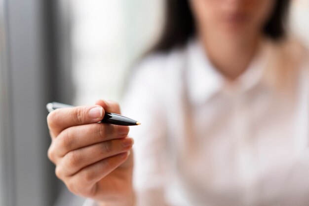 Defocused woman holding pen close up