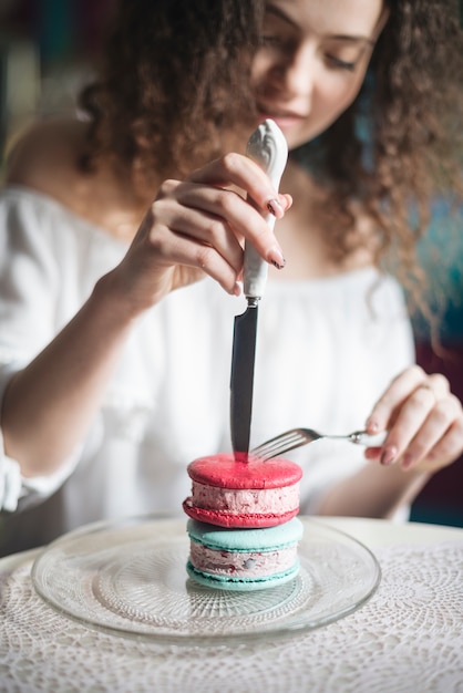 분홍색과 파란색 아이스크림 샌드위치 위에 날카로운 칼과 포크를 삽입하는 defocused 여자