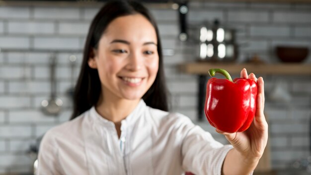 Расфокусированным женщина, держащая красный перец в кухне