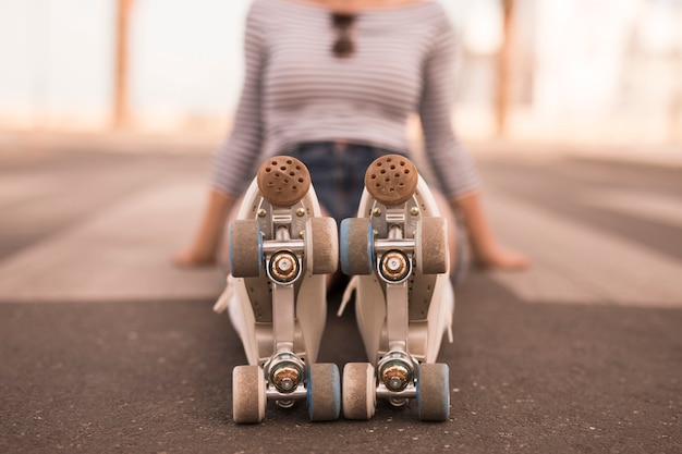 Defocussed young woman sitting on ground with roller skate on her feet