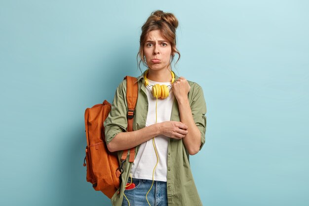 Dejected young woman in low spirit, purses lower lip