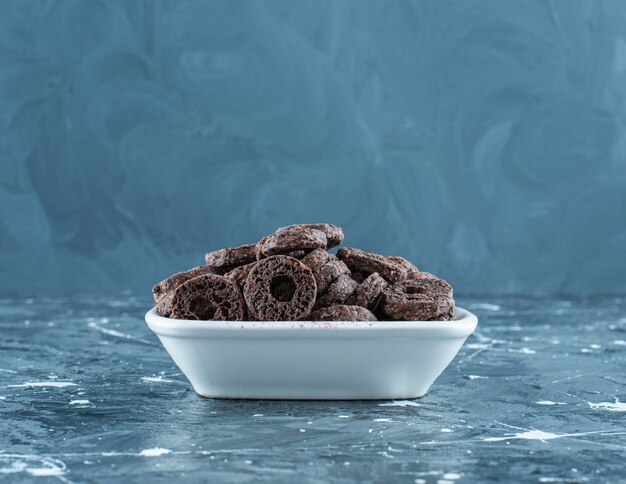 Delectable chocolate coated corn ring in a bowl, on the marble background. 