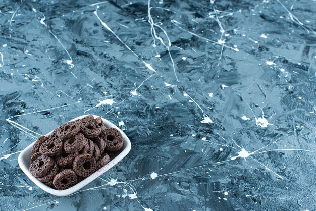 Delectable chocolate coated corn ring in a bowl, on the marble table