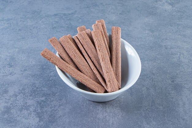 Delectable chocolate wafer roll in a bowl , on the marble background.