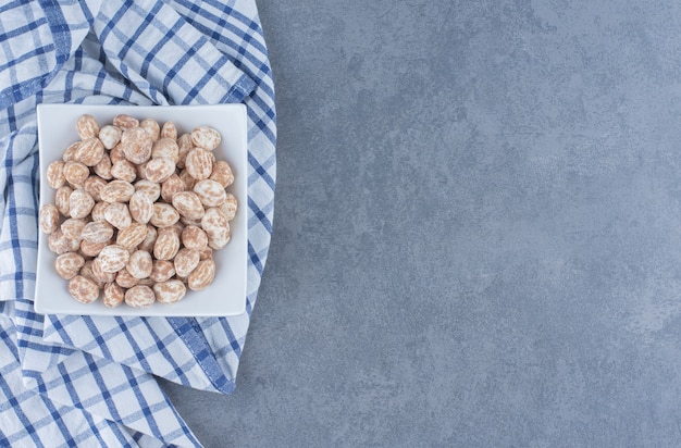 Delectable cinnamon candies in the plate, on the marble background. 