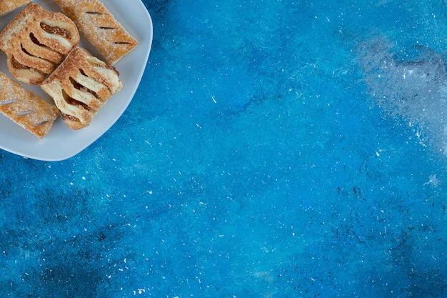 Восхитительное печенье с вареньем на тарелке, на синем фоне. Фото высокого качества