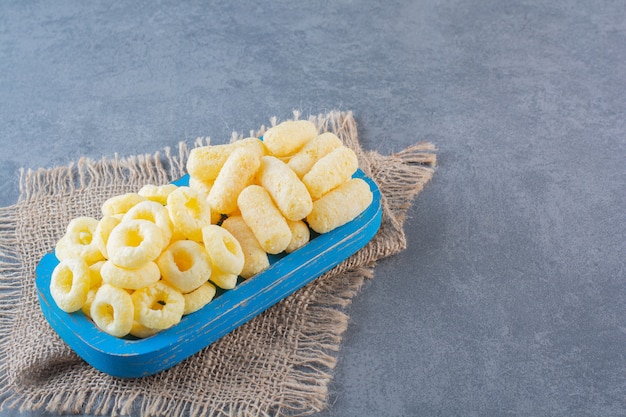 Delectable corn rings on a wooden plate on texture, on the marble surface