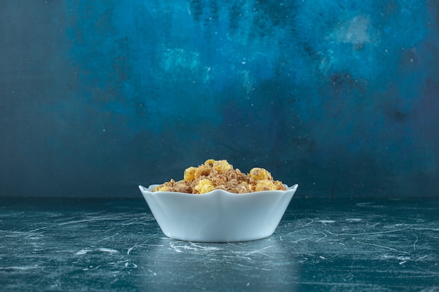 Delectable cornflakes in a bowl , on the blue table. 