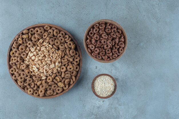 Delectable cornflakes in the wooden bowls , on the blue background.