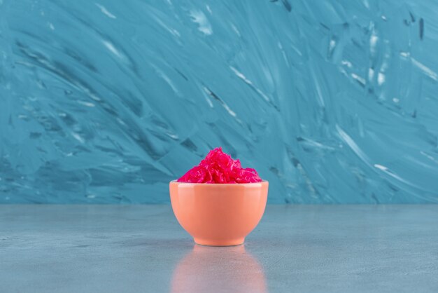 Delectable fermented red cabbage lies in a bowl, on the blue table. 