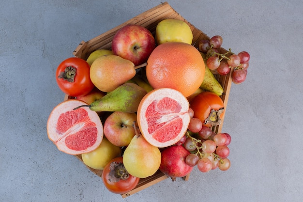 A delectable fruit assortment in a wooden basket on marble background.