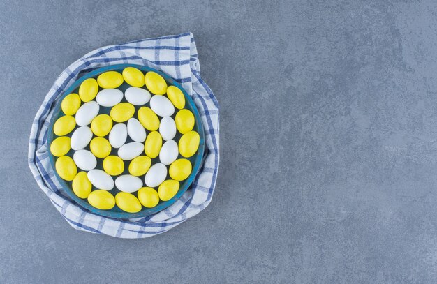 Delectable gums in the bowl on the towel, on the marble background. 